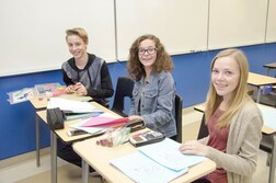 Three elementary schools at their desks smiling