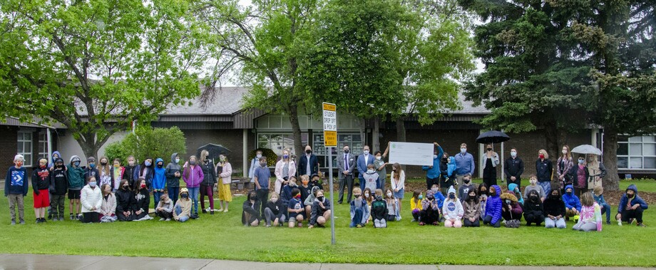 Students in front of the school presenting the cheque