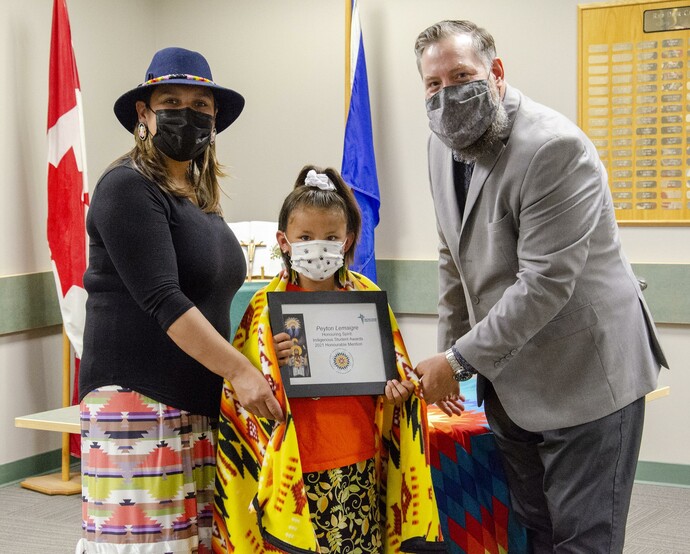 Student holding her award with a mask on